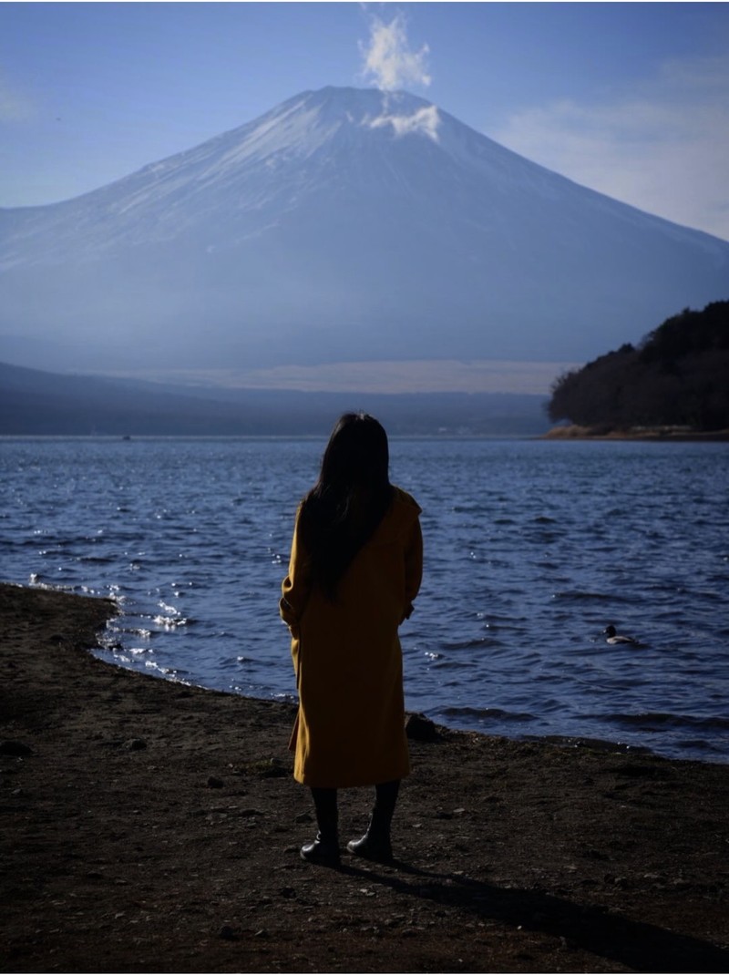 Kaori Rei standing at the edge of a lake, facing Mt. Fuji