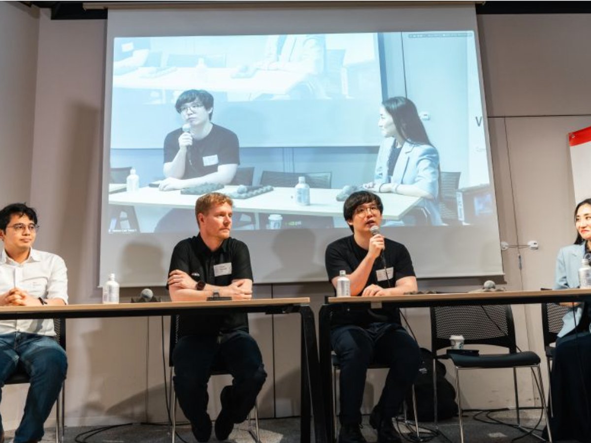 Panel discussion at the Executive AI Adoption Roundtable in Tokyo, four speakers seated with a remote guest joining on screen